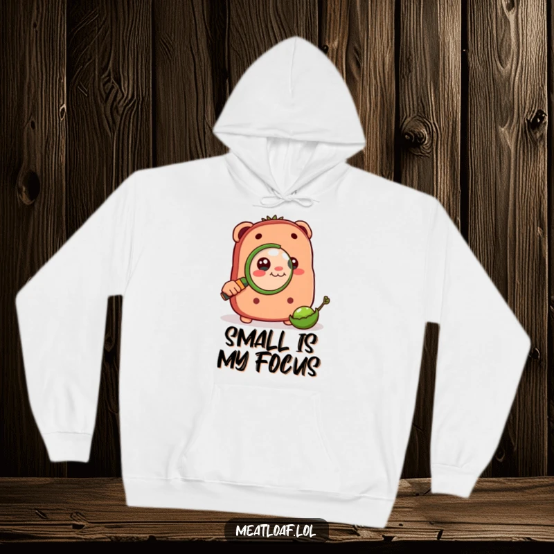 Funny hoodie of a meatloaf character engrossed in examining a tiny pea through a magnifying glass, symbolizing deep thought.